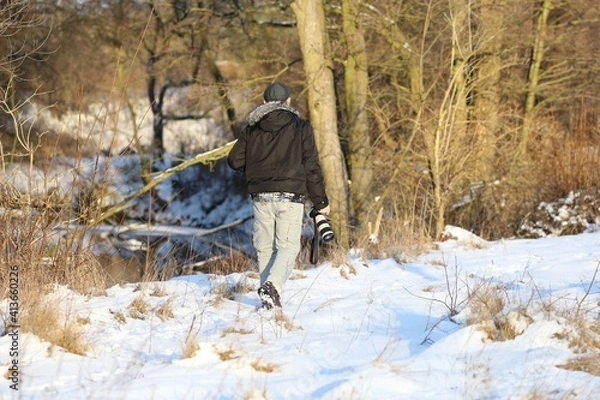 Fototapeta man with a photo camera is walking in winter scenery