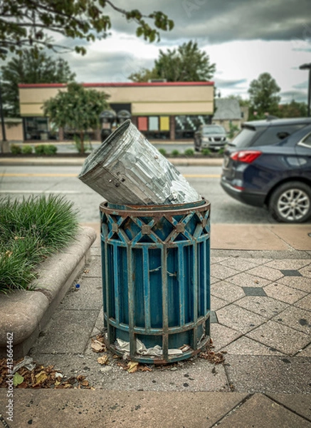 Fototapeta Funny Portrait of a Trash Can Being Thrown Away Inside of a Larger Trash Can