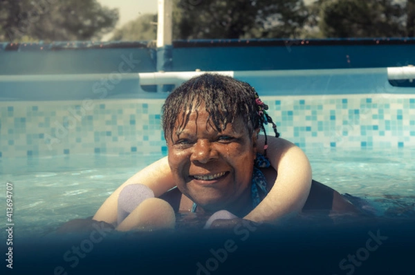Obraz Cheerful smiling African American woman swimming in the pool on a sunny day