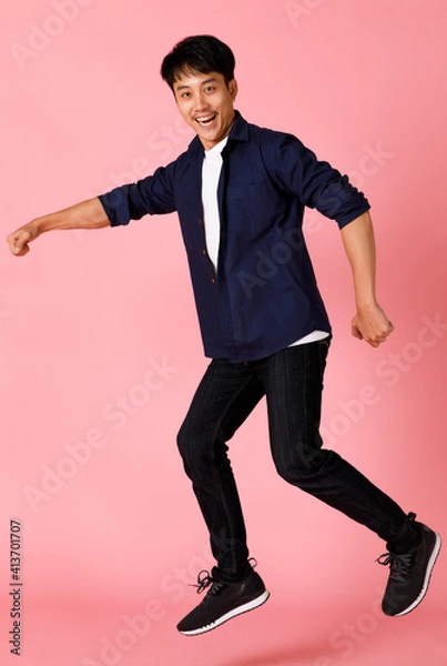 Fototapeta Portrait of young and cute Asian teen posing to camera with self-confidence and happy face. He looks like walking with a funny pose