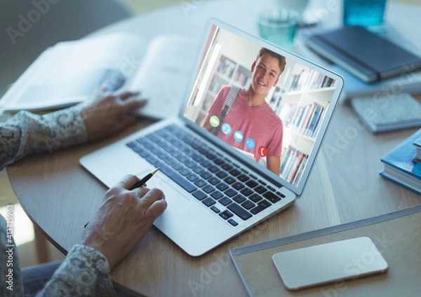 Fototapeta Female teacher having a videocall with male student on laptop at home