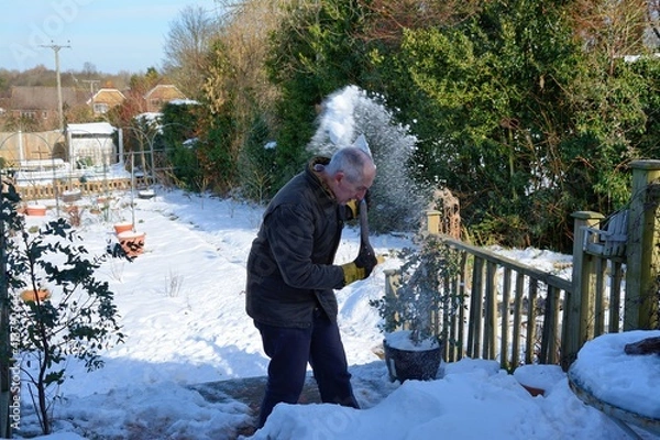 Obraz Senior man clearing snow off his decking .