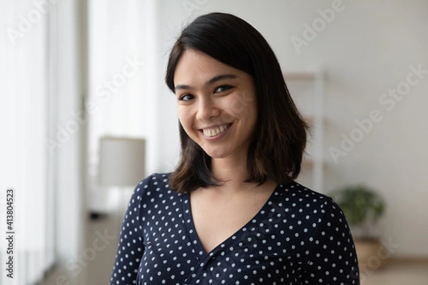 Obraz Headshot portrait of happy millennial female student of asian ethnicity. Confident smiling lady receptionist meet guest. Profile picture of young vietnamese woman blogger tutor looking at web camera