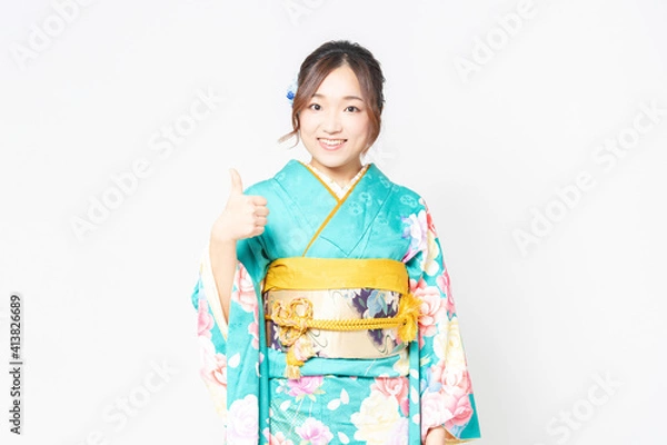 Fototapeta 白背景の前に立って、いいねのジェスチャーをする振袖を着た女性