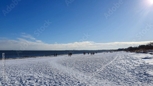 Fototapeta People are walking on a snow-covered beach in Sopot on a beautiful sunny day, Poland