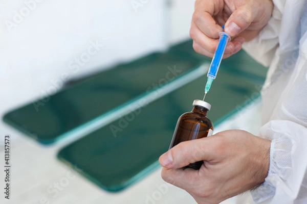 Fototapeta Close-up of a man's hand holding a syringe with a needle and a vaccine against the virus and preparing it for vaccination. Vaccination against coronavirus. Vaccine for pandemic