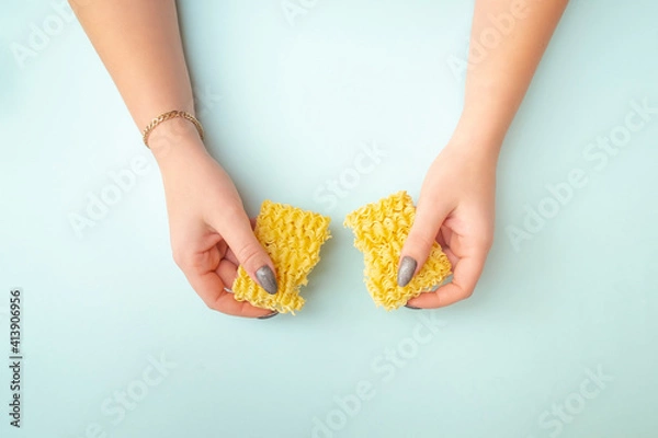 Obraz female hands hold two halves of broken paste. Girl smashed pasta