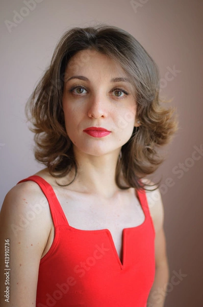 Obraz Indoor female portrait of young attractive woman in red clothes with sensual lips looking at the camera in studio