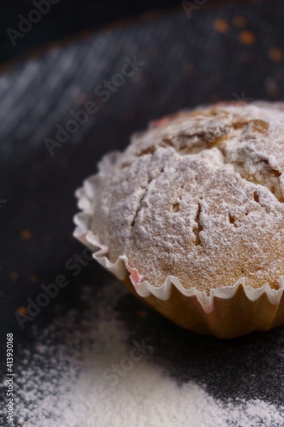 Fototapeta cupcake in powdered sugar on a plate on a black background