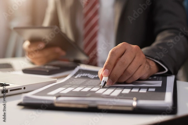 Fototapeta Businessman using a tablet to analysis graph company financial at office in the morning.