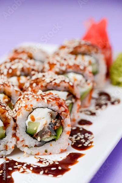 Fototapeta Japanese sushi set with eel and unagi sauce. Cream cheese inside. Served on a white plate.