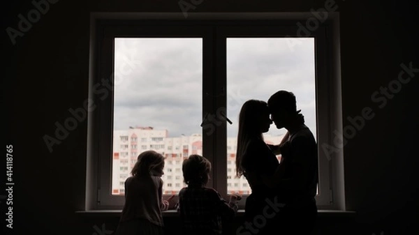 Fototapeta Silhouette of lovers with children on the background of windows from a new apartment.