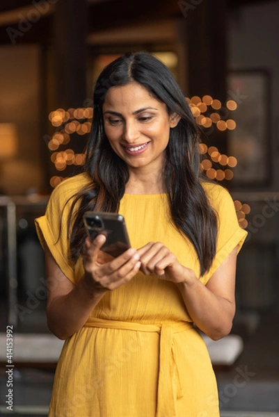 Fototapeta Beautiful Asian Indian woman talking / texting on mobile phone