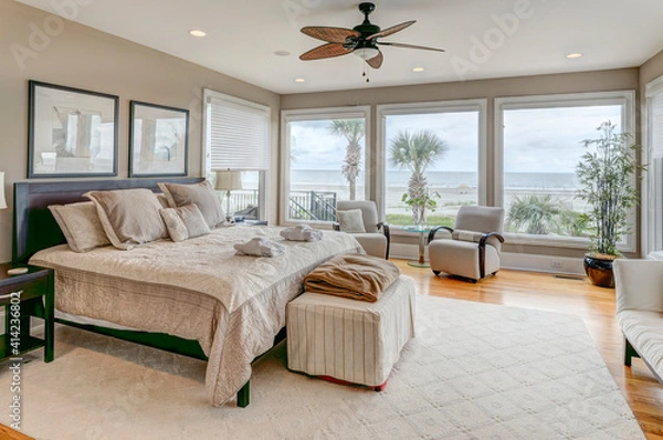 Fototapeta Luxury beach view bedroom looking out onto palm trees and the ocean.