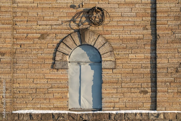Obraz the door in the form of an arch is closed with a sheet of iron. old textured brick building