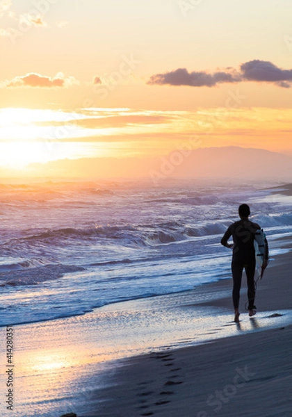 Fototapeta Surfer on the beach running during the sunset