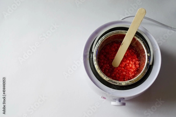 Fototapeta depilation wax heater with melted wax inside and wooden stick on white background