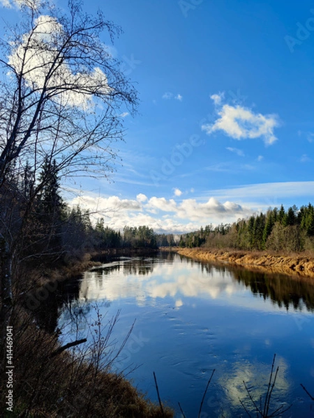 Fototapeta Early winter in Europe. Dark water of a river with a sky reflection in it. River makes a turn. 

