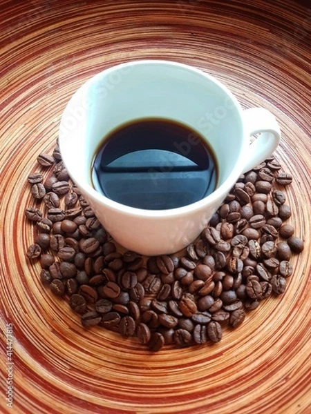 Obraz Coffee cup on circular wooden table with coffee beans.