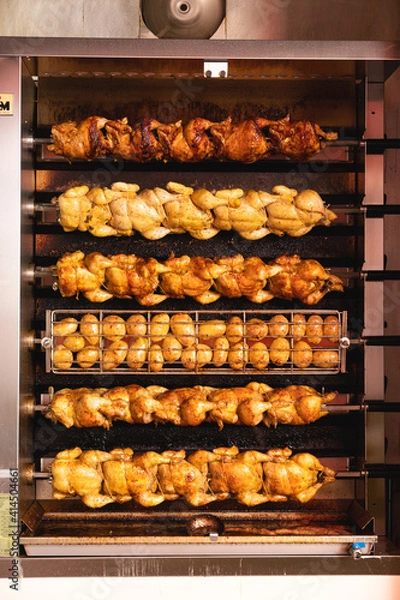 Fototapeta Traditional roasted chicken and potatoes near the entrance to the butcher shop in the city, roasting potatoes and chicken with natural gas