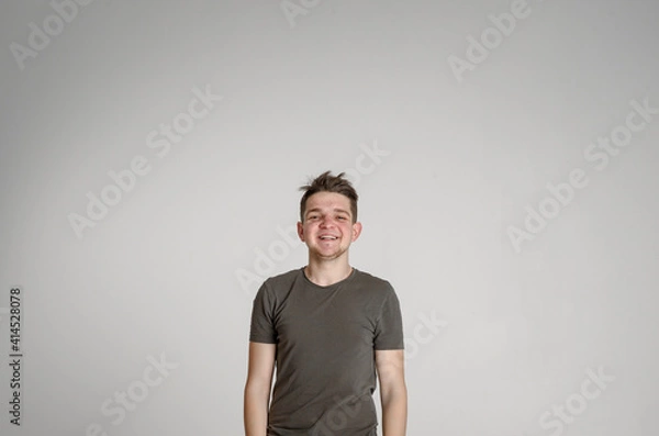 Fototapeta 
teen guy looking at camera happy
 and sincerely smiling with teeth on a white background in a green T-shirt
