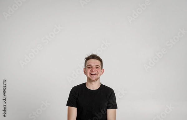 Fototapeta 
teen guy looking at camera
 and sincerely smiling with teeth on a white background in a black T-shirt