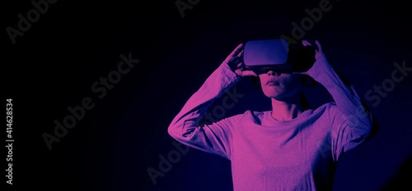 Fototapeta Girl with hands up wearing the VR headset goggles. Asian woman in glasses of virtual reality. The concept of futuristic. Digital VR glasses. Woman getting cyber experience using modern black color VR.