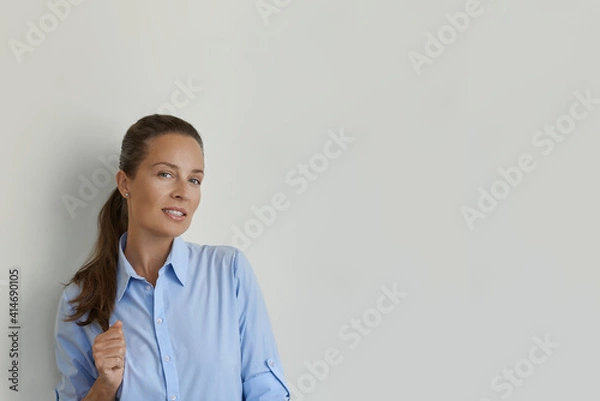 Fototapeta Smiling a female with strong hair, looking at the camera. Studio shot of a beautiful woman, isolated from the empty studio wall.