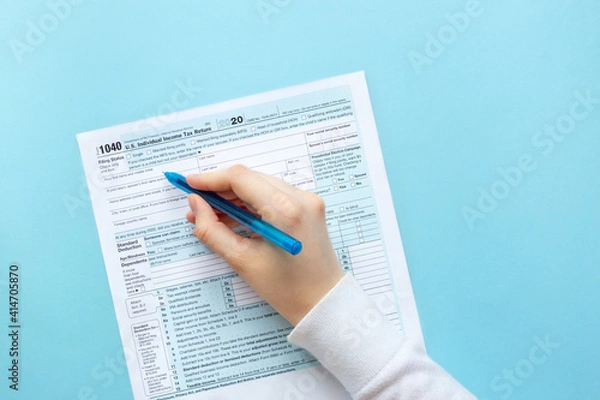 Fototapeta The hand writes with a pen on the 1040 tax form. 1040 Individual Income Tax Return. With copy space, space for text 