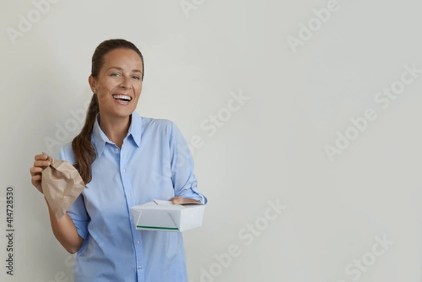 Fototapeta Portrait shot of happy young woman receiving lunch meal box. 