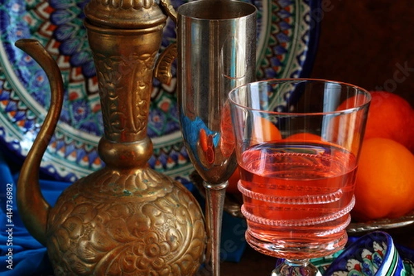 Fototapeta Oriental still life with red wine and oranges on wooden background