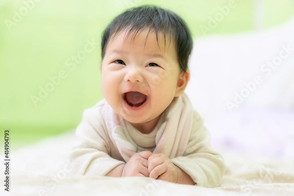 Obraz Asian Happy newborn baby smiling while lying down on the bed. 3 Months cute baby laughing on the bed use as baby development and education concept.