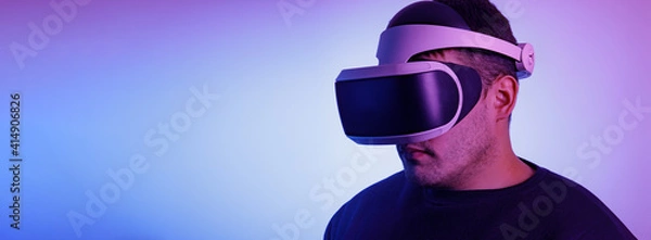 Fototapeta A man in his thirties wearing virtual reality glasses playing video games with a virtual reality headset Fashionable Neon Tinted. Copy space