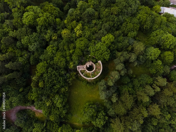 Fototapeta Aerial view of a green landscape with an abandoned building in the forest