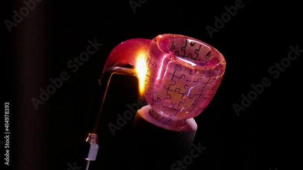 Fototapeta A Lampworker welds a handle to a puzzle patterned bowl made from borosilicate glass 