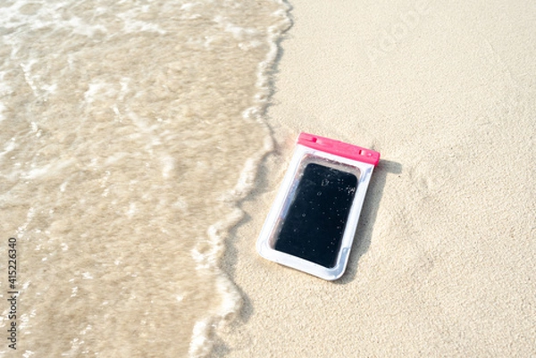 Fototapeta Waterproof case on a smartphone, phone for taking pictures under water. Phone in the waterproof case underwater, on the sands