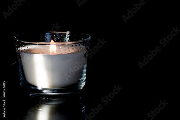 Fototapeta Bright white scented candle flame with dark background.