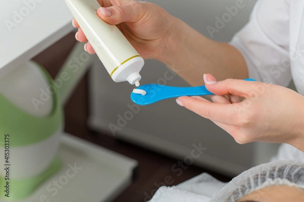 Fototapeta Close-up of a cosmetologist's hand adding cream to the shoulder blade