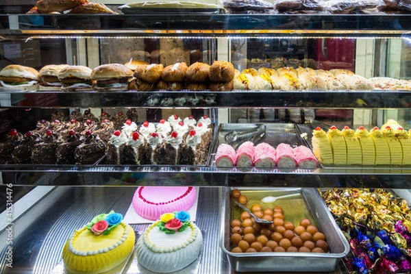 Fototapeta Baked cakes with colourful presentation on display in a glass food display cabinet in Chennai, Tamil Nadu, India