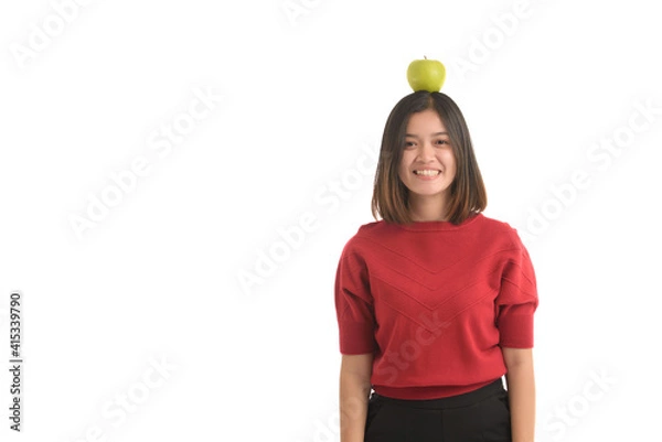 Obraz Asian girl put the apple on his head and smile happily, on white background.