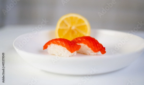 Obraz side view, white plate with sushi and lemon on a white background, red fish on rice