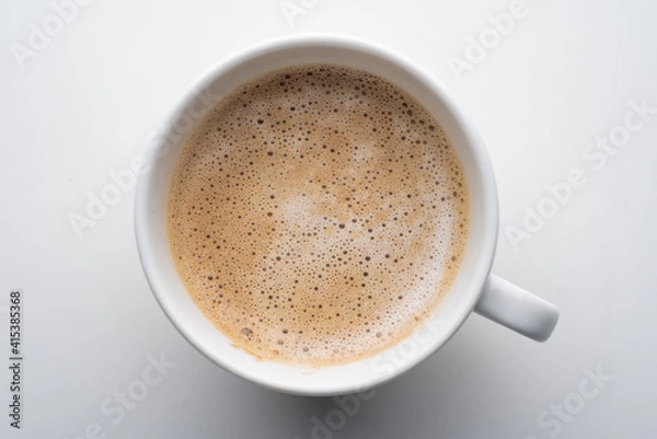 Fototapeta White cup of coffee in soft light isolated on a white background. Cappuccino coffee. Top view