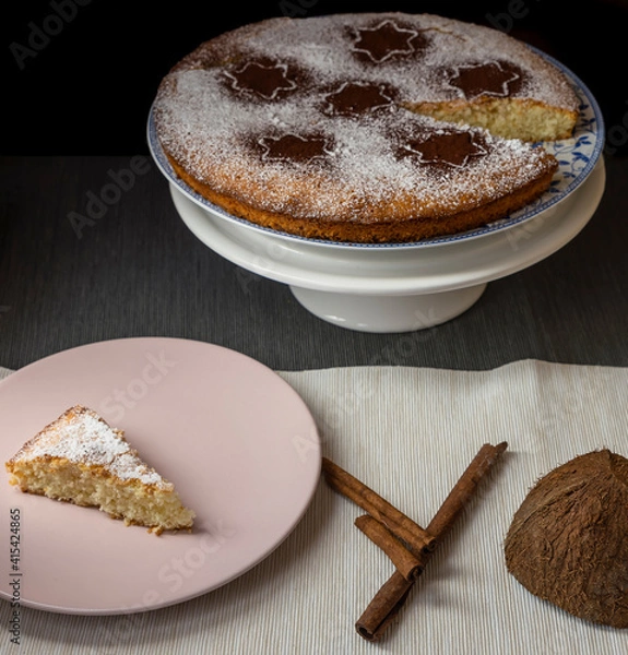 Fototapeta Coconut and lemon cake, covered with powdered sugar and cocoa powder