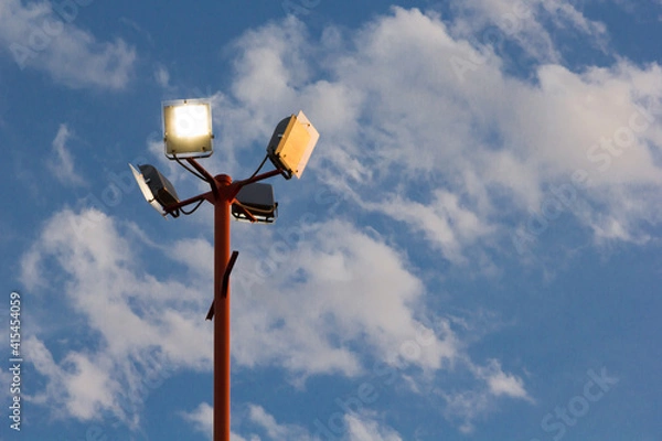 Obraz Poste de luz con varios reflectores con fondo de cielo nuboso