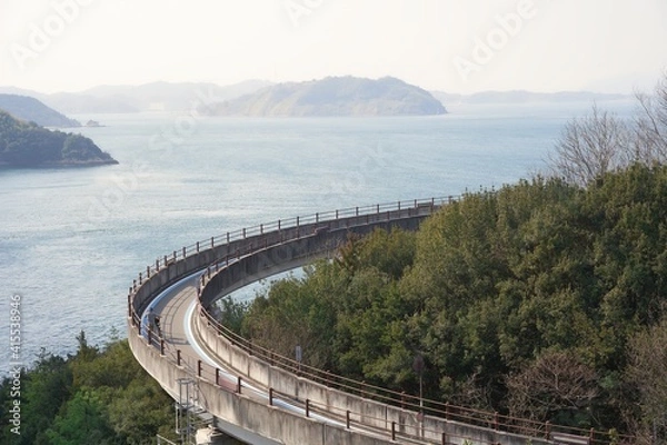 Obraz 日本の来島海峡大橋にある自転車道でサイクリングを楽しむ人　ナショナルサイクルルート「しまなみ海道サイクリングロード」