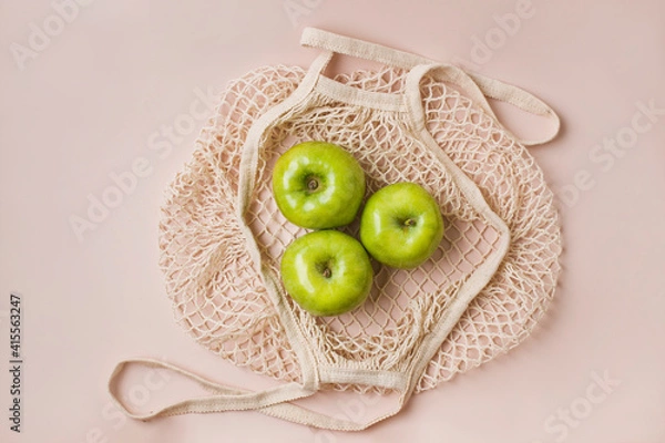 Fototapeta Fashionable mesh string bag with green apples on a gray background. Zero waste and plastic free concept. Copy space.