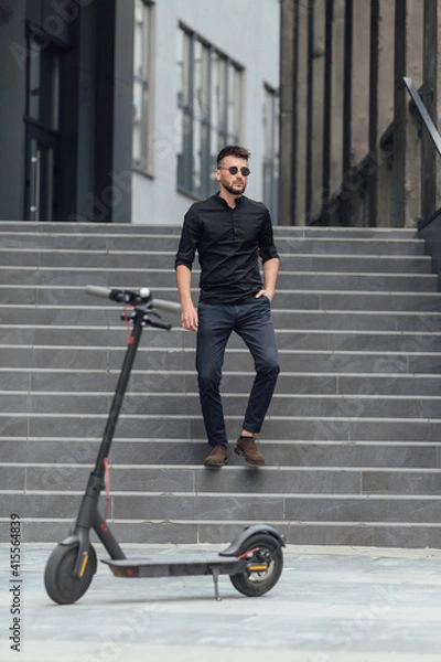 Fototapeta Young man going downstairs  to his electric scooter in urban background