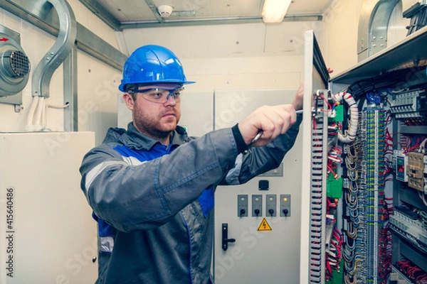 Fototapeta Energy and electricity, electromechanical protective at work with an electric panel, an electrician diagnoses electrical distribution panels in an electrical panel, toned