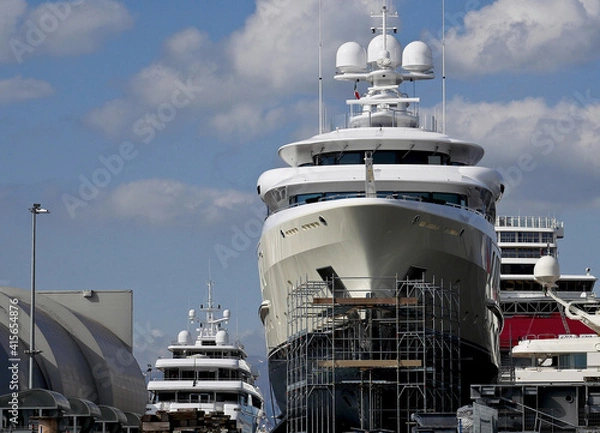 Fototapeta Luxury yachts in a shipyard with scaffolding on the hull