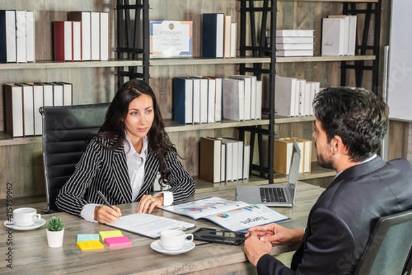 Obraz A woman boss businesswoman shaking hand with a businessman candidate at an office desk in an interview or meeting.